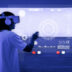 A person wearing a virtual reality headset and headphones, reaching out to interact with a futuristic, holographic interface in blue tones.