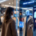 Woman using a smart mirror technology in a modern clothing store, viewing digital outfit suggestions. - AI trends and breakthroughs 2025